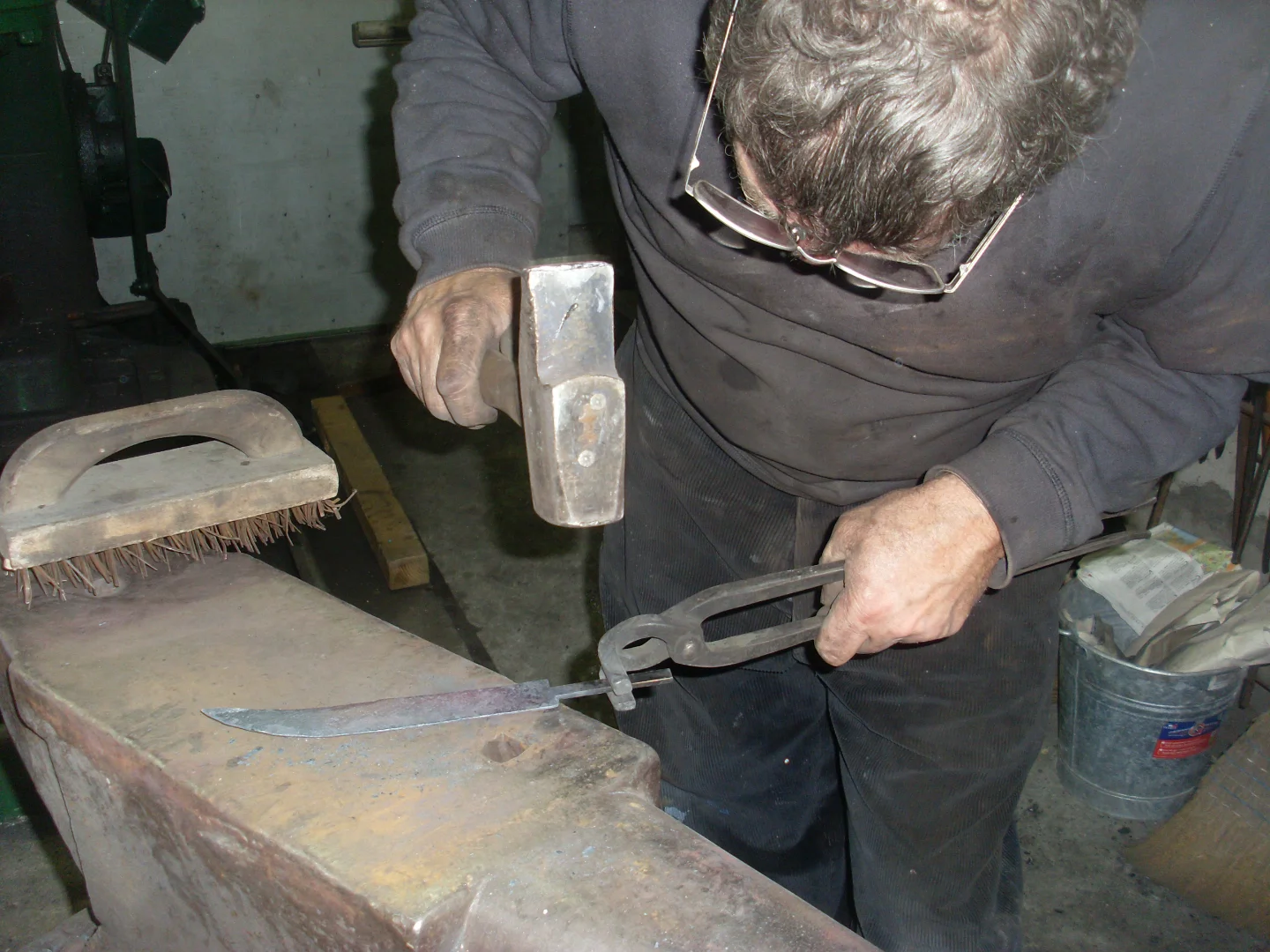 Artisan forgeant une lame du couteau Le Possonnéen dans l'atelier d'affûtage, illustrant le savoir-faire artisanal