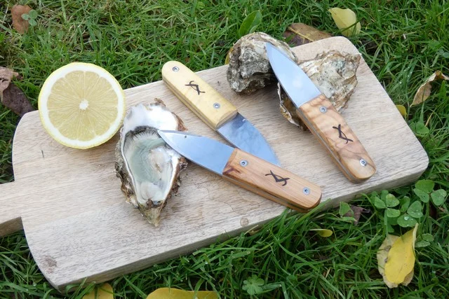 3 couteaux à huîtres artisanaux (Little Robert) posés sur planche en bois avec des huîtres et du citron.